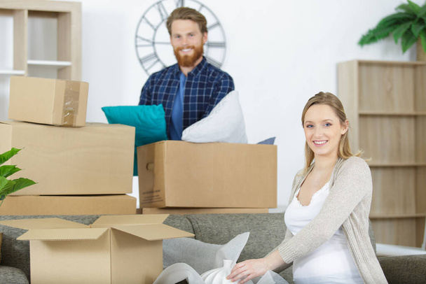 pregnant couple unpacking boxes in their new home - Foto, Bild