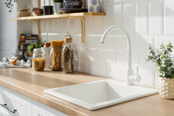 白いトーンで北欧のキッチンインテリアデザインに白いシンク。装飾器具の概念を持つ木製の棚。背景にある食品 - 写真・画像