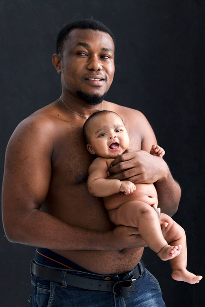 Pequeña niña asiática recién nacida en el abrazo de su padre fondo negro, retrato de dulce bebé adorable en brazos del padre, padre sosteniendo al bebé. - Foto, imagen
