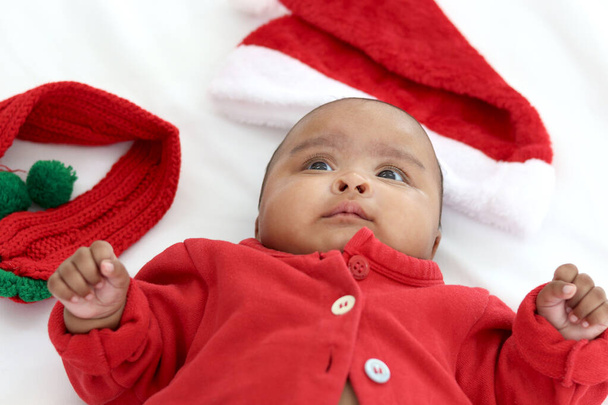 Маленька азійська новонароджена дівчинка в костюмі червоної сукні для святкування Різдва лежачи на білому ліжку в спальні, портрет милого малюка.. - Фото, зображення