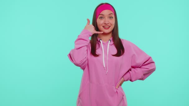 Teenager Mädchen in rosa Kapuzenpulli schaut in die Kamera und macht Handygesten wie sagt hey du rufst mich zurück - Filmmaterial, Video