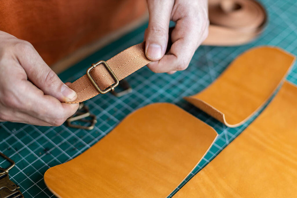 Process cutting scheme of bag with equipment and materials. Male tanner working at leather workshop - 写真・画像