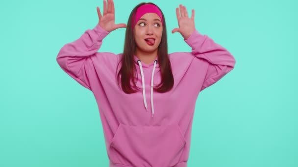 Αστεία έφηβος κορίτσι κάνει παιχνιδιάρικο ανόητο εκφράσεις του προσώπου και γκρίνια, χαζεύοντας γύρω δείχνει τη γλώσσα - Πλάνα, βίντεο