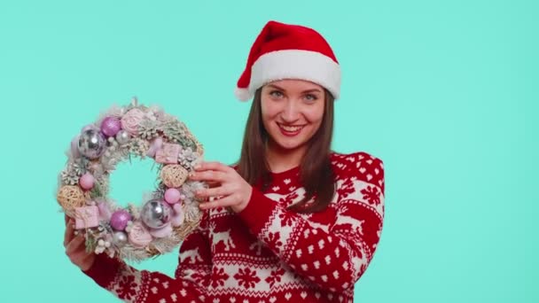 Взрослая улыбающаяся девушка в красном рождественском свитере держит указательный палец на праздничной игрушке - Кадры, видео
