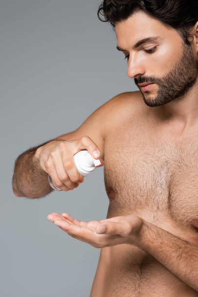 bearded and shirtless man holding foam cleanser isolated on grey - Фото, зображення