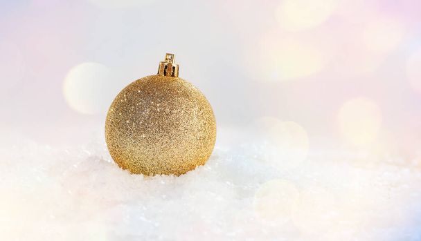 Χρυσή λαμπερή χριστουγεννιάτικη μπάλα στο χιόνι σε ένα ελαφρύ φόντο.Χριστούγεννα και το νέο έτος Glitter, γυαλιστερό φόντο.Χριστουγεννιάτικη σύνθεση.Χριστούγεννα, χειμώνας, το νέο έτος έννοια.διακοσμήσεις σπίτι.. - Φωτογραφία, εικόνα