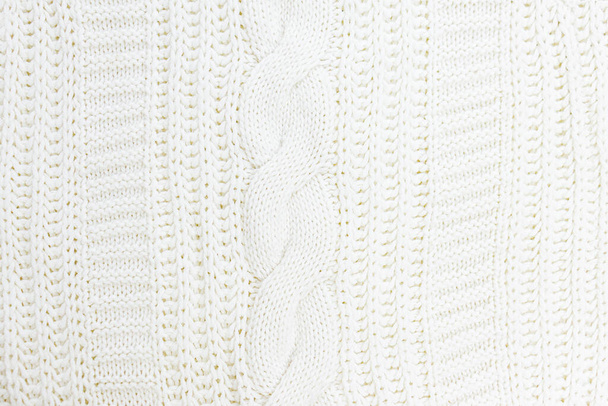 The texture of a fragment of a knitted woolen sweater in white. Selective focus.Knitted white sweater background texture. Milky white color. - Foto, afbeelding