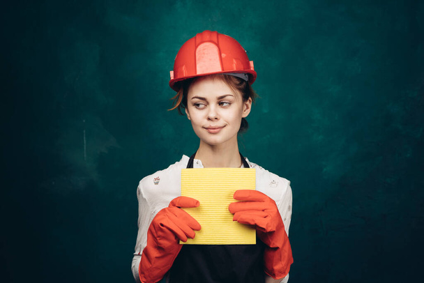 woman in black apron orange hard hat protection cleaning - Фото, изображение