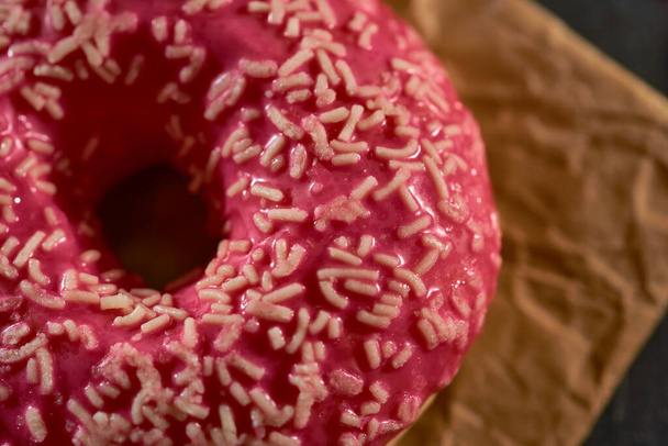 Rosafarbener Donut auf einer schwarzen Tafel in der Küche - Foto, Bild