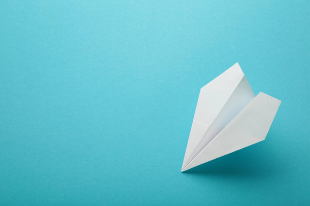 White paper airplane on a blue background. Top view - Foto, Bild