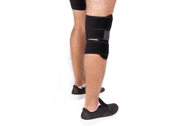 Knee Support Brace on leg isolated on white background. Orthopedic Anatomic. Braces for knee fixation, injuries and pain. Knee Joint Bandage Sleeve. Elastic Sports - 写真・画像