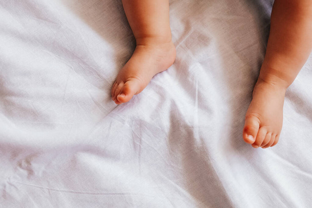 cute 6 month baby feet on white sheet - Zdjęcie, obraz