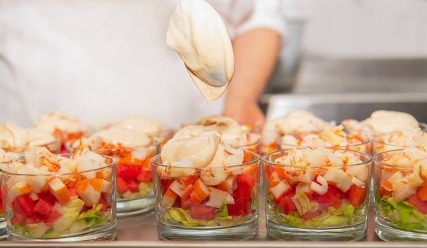 Szklanki z posiekanymi krewetkami z arbuzem, paluszkami krabowymi, sałatą, różowym sosem i pietruszką - Zdjęcie, obraz