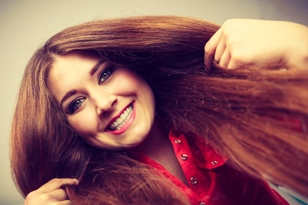 Happy positive woman with long brown hair presenting her healthy hairdo. Haircare concept. - Fotografie, Obrázek