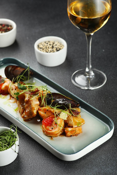 seafood plate with mussels and shrimp toped microgreen closeup with glass of white wine. - Фото, изображение