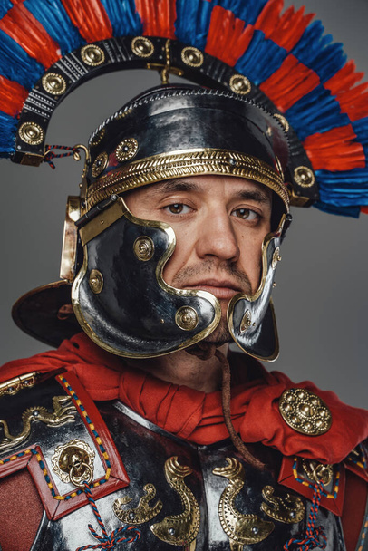Starověký císařský legionář s helmou na šedém pozadí - Fotografie, Obrázek