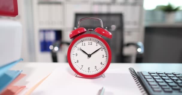 Красный будильник на десять часов с большим количеством папок на столе - Кадры, видео