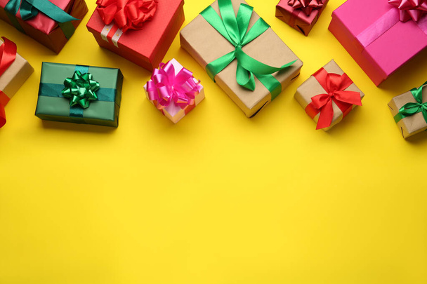 Many colorful gift boxes on yellow background, flat lay. Space for text - Foto, Imagem