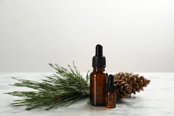 Pine essential oil, cones and branch on white marble table - Foto, immagini