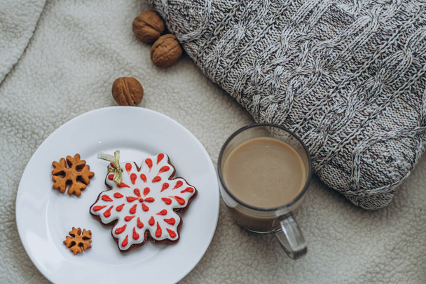 Vánoční kompozice s perníkovými sušenkami a kávou. Vynikající jídlo na talíři. Útulná sváteční atmosféra. Mléko texturované pozadí se svetrem. - Fotografie, Obrázek