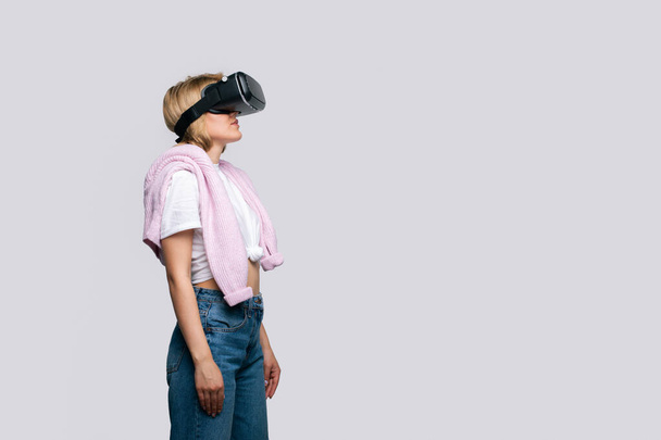 A virtuális videószemüveget használó fiatal nő oldalnézete visszatér a szövegtérbe. VR tapasztalat. Másold a helyet. Elszigetelve, fehér háttérrel. Modern női életmód - Fotó, kép