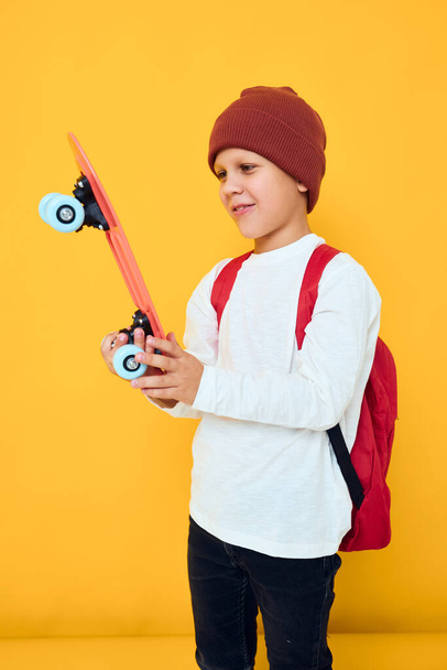 portrait of cute boys with red backpack red skateboard Childhood lifestyle concept - Foto, afbeelding