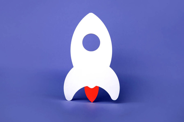 raket op een paarse achtergrond, een symbool van een nieuwe startup - Foto, afbeelding