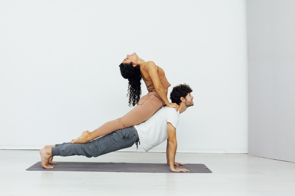 a woman and a man engaged in paired gymnastics yoga asana - Foto, imagen