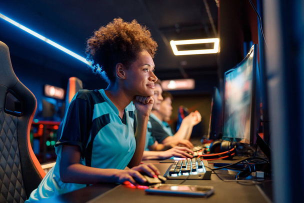Skillful woman gamer practicing in gaming arena in internet club - Foto, imagen