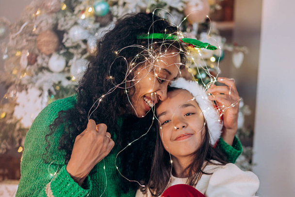 Black mother and daughter pose wrapped with garland - Photo, Image