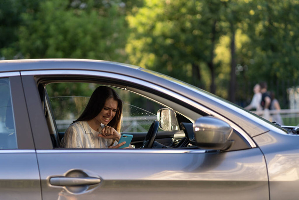 Síró fiatal lány olvasott üzenetet a mobilján. Frusztrált feldúlt fiatal nő a vezetőülésnél autóban - Fotó, kép