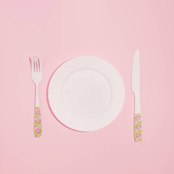 Minimales Layout aus Teller, Gabel und Messer auf pastellrosa Hintergrund. Dinner-Idee für Feiertage. - Foto, Bild