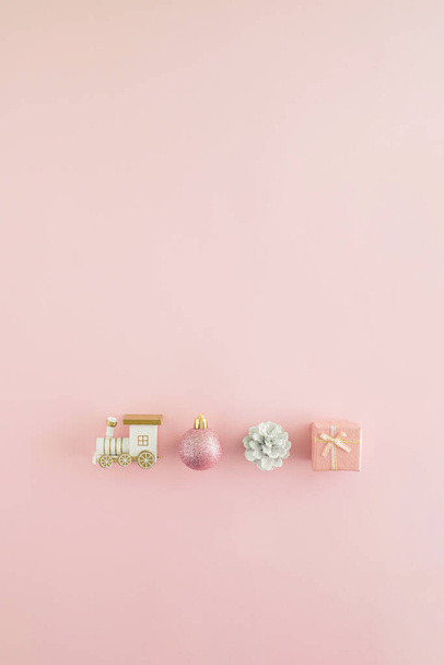 Creative arrangement made of locomotive and New Year's stuff on a pastel pink background. Minimal vertical flat lay concept. Christmas phone wallpapers. Gift delivery inspiration. - Photo, Image