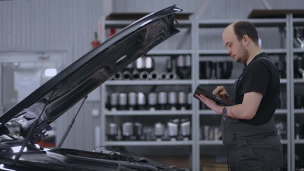Using Digital Tablet For A Car Diagnostic. mechanic using a tablet pc at the repair garage . Interactive Diagnostics Software on an Advanced Computer. - Footage, Video