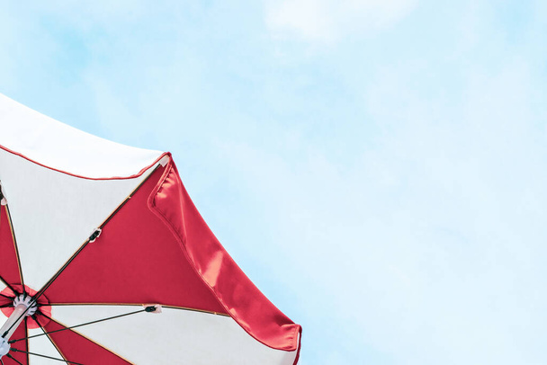 Plage de parapluies. Parasol de plage d'été rouge sur fond bleu de mer. pare-soleil pour les voyages de vacances. Vacances de détente en plein air à l'océan avec espace de copie - Photo, image