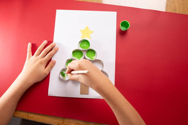 Kid making abstract Christmas tree, toilet paper roll reuse for child activity - Photo, image