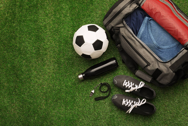 Gym bag and sports equipment on green grass, flat lay. Space for text - Fotoğraf, Görsel