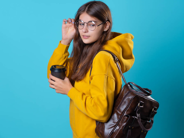 Un jeune étudiant en sweat à capuche jaune avec une tasse de café en carton à emporter. - Photo, image