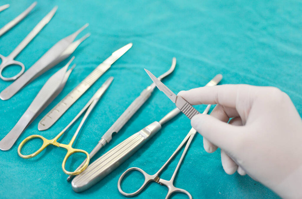 Hand hält chirurgische Instrumente im Operationssaal. - Foto, Bild