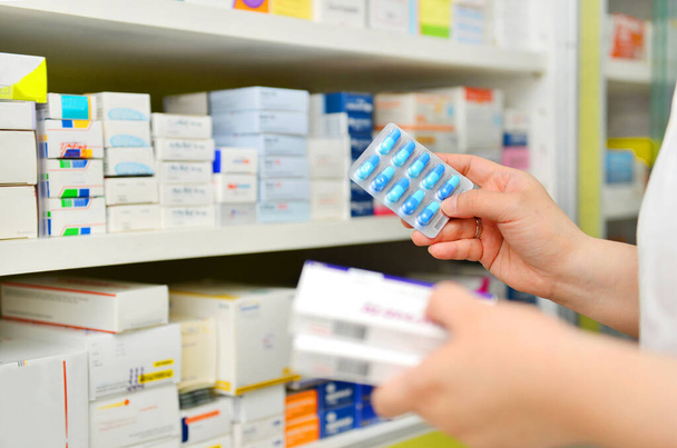 Pharmacist holding medicine box and capsule pack in pharmacy drugstore - Photo, Image