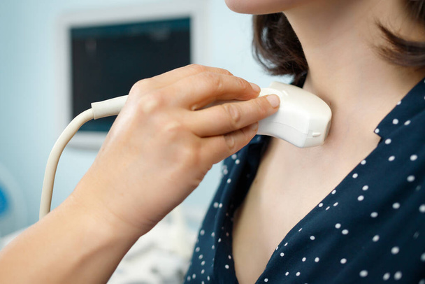Diagnostic examining patient woman thyroid gland using ultrasound scanner machine, close-up hands. - Zdjęcie, obraz