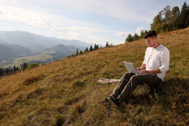 Людина працює з ноутбуком на відкритому повітрі в оточенні красивої природи. Простір для тексту
 - Фото, зображення