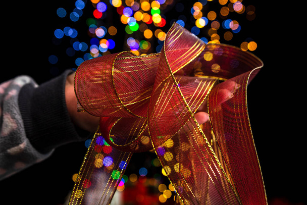 Holding Christmas decoration against bokeh lights background - Foto, Imagem