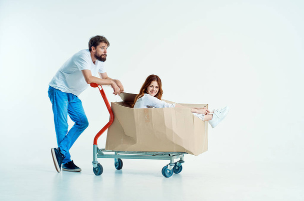 a young couple shipping transport in a box light background - Foto, afbeelding