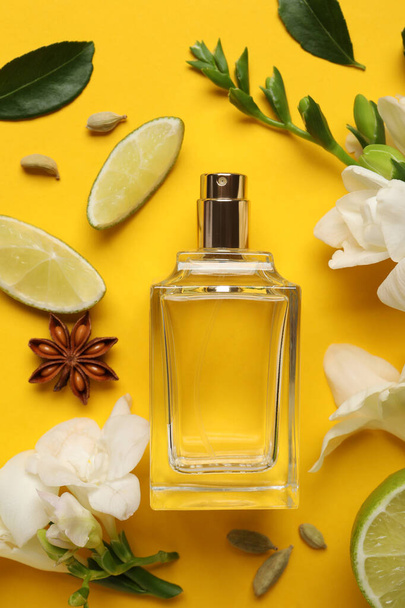 Flat lay composition with bottle of perfume and fresh citrus fruits on yellow background - Foto, Imagen