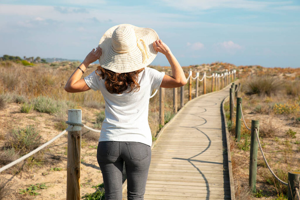 woman tourist walking on wooden path across the dunes - Photo, Image