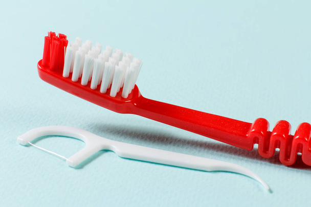 Γκρο πλαν άποψη μιας οδοντόβουρτσας και μια οδοντογλυφίδα σιλικόνης στο μπλε φόντο. Ρηχό βάθος πεδίου. - Φωτογραφία, εικόνα