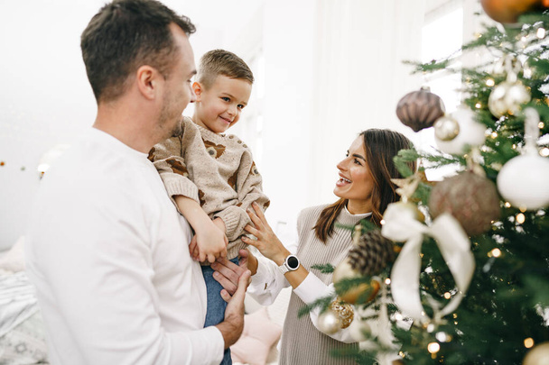 Dreiköpfige Familie schmückt zu Hause einen Weihnachtsbaum - Foto, Bild