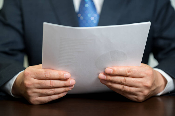 Un hombre de negocios sosteniendo un documento de libro blanco. - Foto, imagen