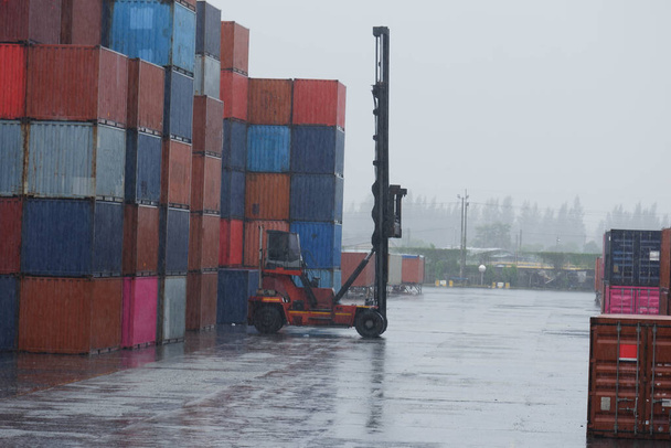 konteynır taşıyıcısı yağmur altında çalışan konteynırları hareket ettiriyor - Fotoğraf, Görsel